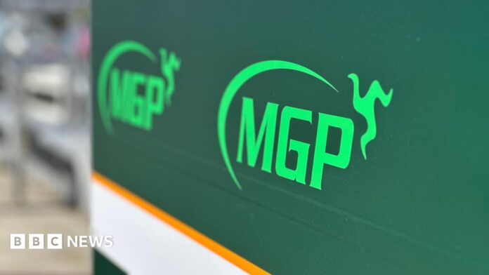 Rider dies after Manx Grand Prix qualifying crash A large green sign with the MGP logo on it in pitlane.